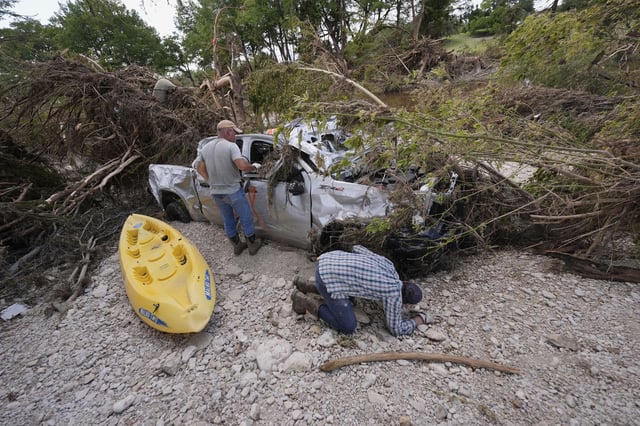 Kevin Scott, Danny LeBourgeois and Lincoln Edwards search for Aiden Heartfield, who went camping with friends and is missing, around a damaged truck along the Guadalupe River after flooding in Kerrville, Texas on Wednesday, July 9, 2025.