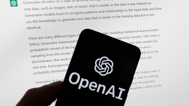 The OpenAI logo is seen on a mobile phone in front of a computer screen displaying output from ChatGPT in 2023. OpenAI is close to releasing an AI-powered web browser, three people familiar with the matter told Reuters