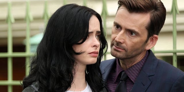 Jessica Jones (Krysten Ritter) staring ahead with a distressed expression while Kilgrave (David Tennant) hovers close