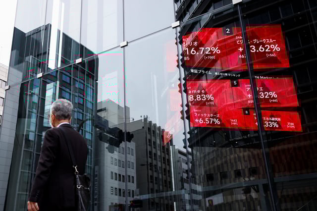 A man walks past an electronic board showing stock visualizations outside a brokerage, in Tokyo, Japan, March 17, 2023. REUTERS/Androniki Christodoulou/File Photo