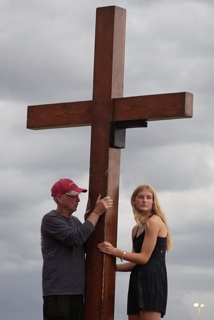 Dan Beazley, of Michigan, left, and Abigail Smithson hold a large cross during a vigil for flooding victims at Tivy Antler Stadium on Wednesday, July 9, 2025, in Kerrville, Texas. (AP Photo/Gerald Herbert)