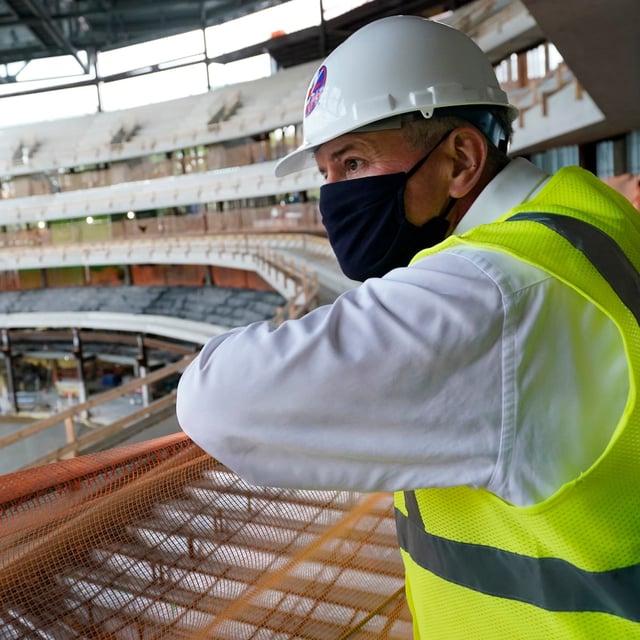 Oak View Group co-founder Tim Leiweke looks over a construction fence as construction continues on the New York Islanders new UBS Arena, Wednesday, Oct. 7, 2020, in Elmont, N.Y. The arena will be home to the New York Islanders NHL hockey club and will also be used for musical concerts. For hockey, the arena's capacity will be around 17,000 fans, and for concerts, around 19,000 people. (AP Photo/Kathy Willens)