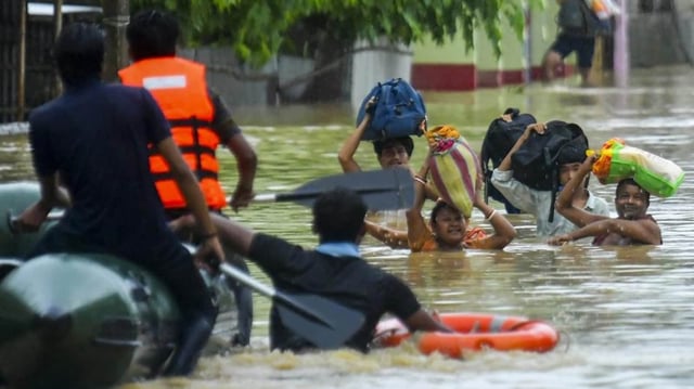 Rescue personnel assist locals in moving to a safer place through a rescue boat in a flood-affected area amid heavy rainfall on the outskirts of Agartala, Tripura.