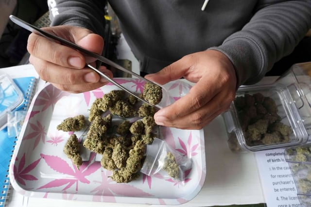 Staff prepares marijuana for a customer at a cannabis shop after Thailand started banning the sale of cannabis to those without a prescription in Bangkok on June 27. Photo: AP