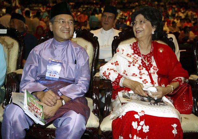 FILE - Former Malaysian Prime Minister Mahathir Mohamad, left, and his wife Siti Hasmah smile as they attend at the general assembly during United Malays National Organization (UMNO) 58th anniversary celebration in Kuala Lumpur, Sept. 23, 2004. (AP Photo/Vincent Thian,File)