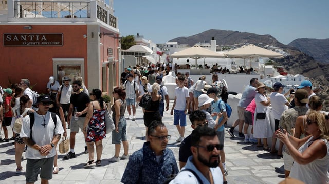 Touristen besuchen das Dorf Oia auf der Insel Santorini, Griechenland.