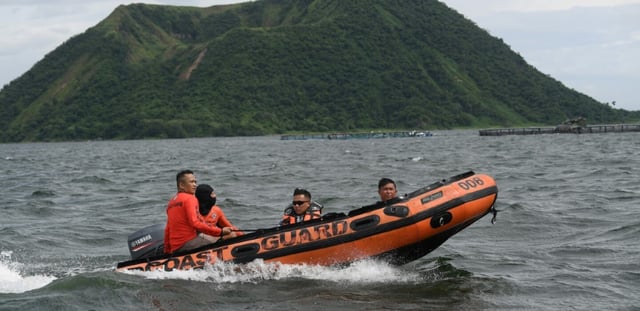 Des garde-côtes à bord d'un bateau pneumatique se dirigent vers le site où les corps personnes liées aux combats de coq sauraient été jetés dans le lac Taal, au sud de Manille, le 10 juillet 2025 aux Philippines