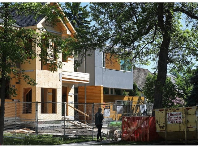  A pedestrian walks their dog past an under construction infill home in Edmonton’s Parkallen neighbourhood in 2024.