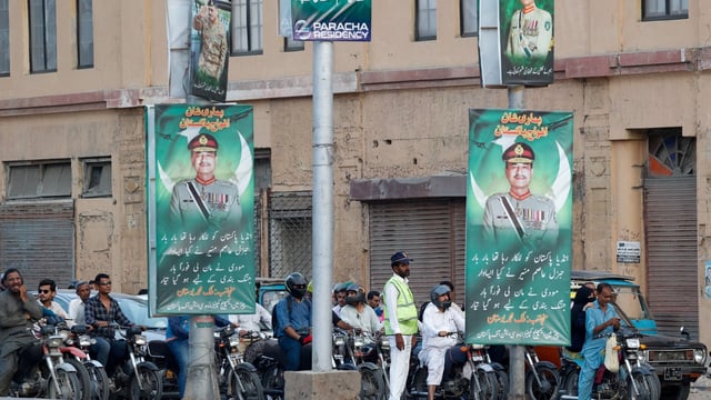 FILE PHOTO: A police officer stands in front of the traffic, next to posters of the Chief of Army Staff of Pakistan Asim Munir, in Karachi, Pakistan May 20, 2025. REUTERS/Akhtar Soomro/File Photo