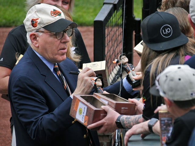 Orioles owner David Rubenstein, left, signs  his bobble-head dolls for fans before game against the Cincinnati Reds at Camden Yards. (Kenneth K. Lam/Staff)