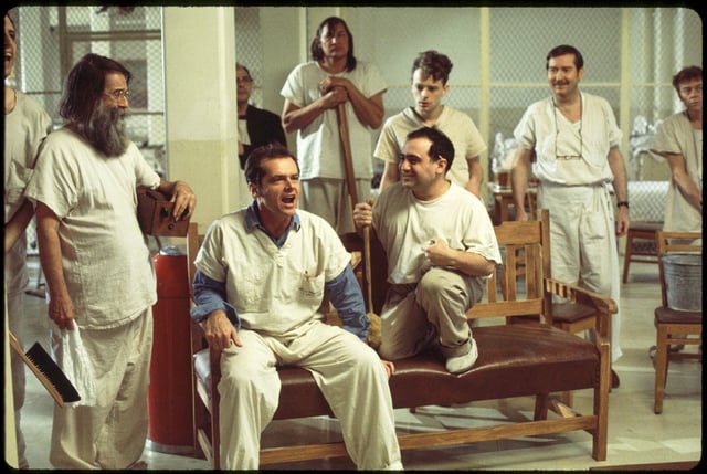 This image released by Fathom Entertainment shows Jack Nicholson, seated left, and Danny DeVito, seated right, with supporting cast in a scene from "One Flew Over the Cuckoo's Nest." (Fathom Entertainment via AP)