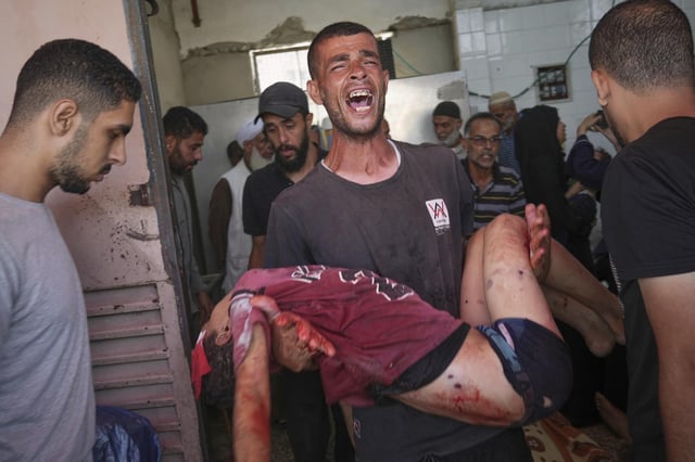 Un hombre lleva en brazos el cuerpo de su sobrino, uno de los 10 niños muertos en el ataque israelí contra un punto de distribución médico en Deir el Balah, en el centro de Gaza.