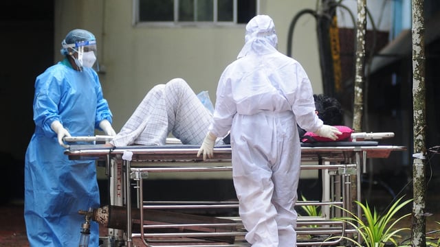 Health workers wearing protective gears shift a man with symptoms of Nipah virus to an isolation ward at a government hospital, in Kozhikode