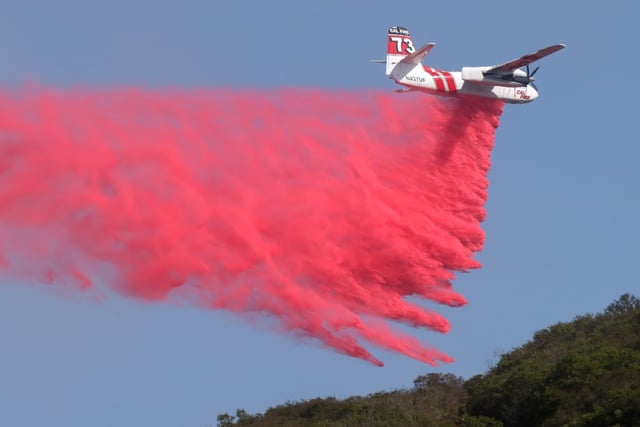 A Cal Fire tanker drops fire retardant on a brushfire in the hills above San Marcos and Carlsbad on Thursday. (Hayne Palmour IV / For The San Diego Union-Tribune)