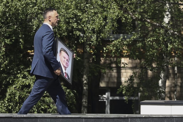 A man carries a portrait of Roman Starovoit, the former transport minister who died in an apparent suicide after his dismissal while people line up to his bid farewell, at the morgue of the Central Clinical Hospital in Moscow, Russia, Thursday, July 10, 2025. (AP Photo)