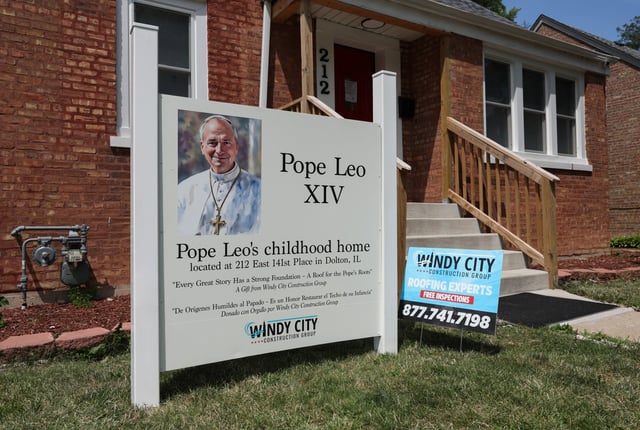 A sign with a painting and name of Pope Leo XIV is posted on the front lawn of his childhood home at 212 East 141st Place, July 2, 2025, in Dolton. A roofing company renovated the home&#39;s roof shingles and placed the sign on the lawn the previous day, according to a Dolton police officer who was posted in front of the structure. (John J. Kim/Chicago Tribune)