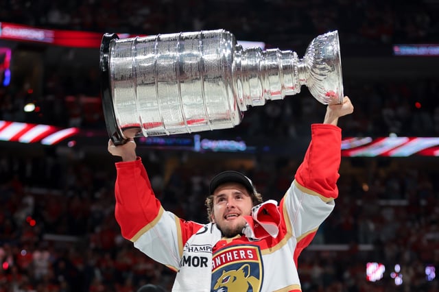Jun 17, 2025; Sunrise, Florida, USA; Florida Panthers right wing Mackie Samoskevich (25) hoists the Stanley Cup after winning game six of the 2025 Stanley Cup Final against the Edmonton Oilers at Amerant Bank Arena. Mandatory Credit: Sam Navarro-Imagn Images/File Photo