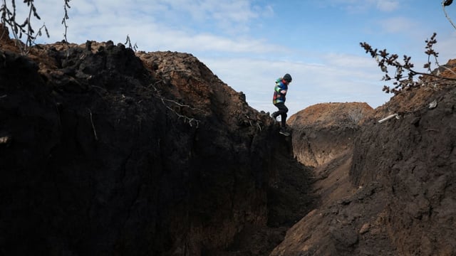 Andrii Tupkalenko, 8, one of the last children left in his frontline village, plays in a trench in the outskirts of Kalynove, Kharkiv region, Ukraine in April.