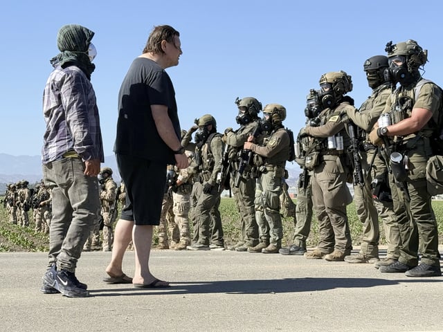 Demonstrators confront federal agents blocking a road during an immigration raid in Camarillo, Calif. (AP Photo/Michael Owen Baker)