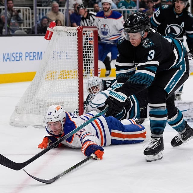 Edmonton Oilers left wing Zach Hyman (18) dives after the puck next to San Jose Sharks defenseman Henry Thrun (3) during the second period of an NHL hockey game Thursday, April 3, 2025, in San Jose, Calif. (AP Photo/Godofredo A. Vásquez)