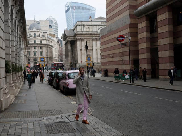 An office worker walks by the City of London financial district, in London, Britain, January 17, 2025. REUTERS/Isabel Infantes/File Photo