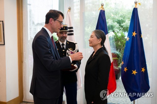 South Korean artist Kimsooja (R) receives the French Order of Arts and Letters with the rank of "officer" from French Ambassador to Korea Philippe Bertoux (L) at the ambassador's residence in Seoul on July 9, 2025, in this photo taken by Kim Jin-sol and provided by her studio. (PHOTO NOT FOR SALE) (Yonhap)