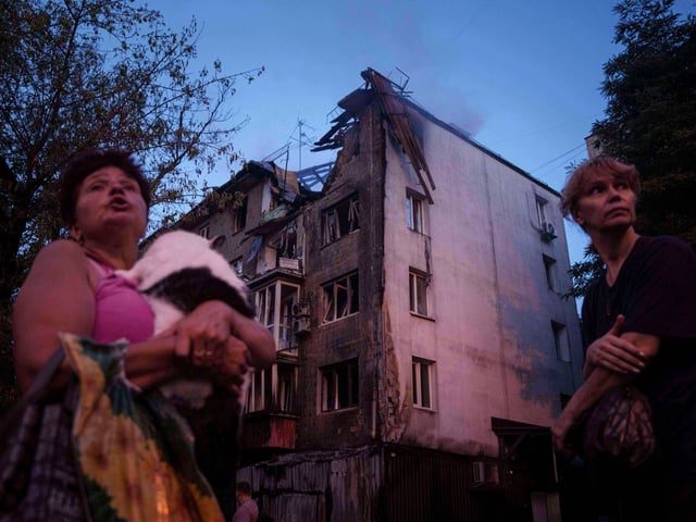 Zwei ukrainische Frauen vor einem zerstörten Haus