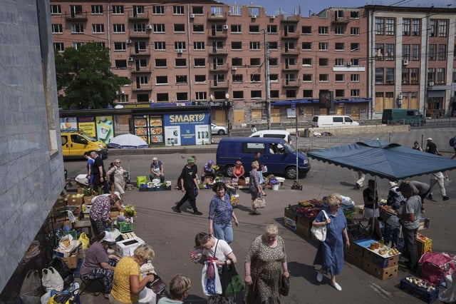 People shop at a street market near a building which was damaged by a Russian attack in Kyiv, Ukraine, on Thursday, July 10, 2025. (AP Photo/Evgeniy Maloletka)