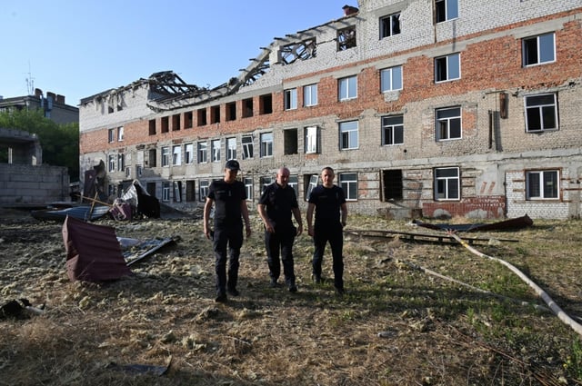 Des secouristes devant un immeuble résidentiel endommagé par une attaque de drone russe, dans le centre de Kharkiv, le 11 juillet 2025 en Ukraine
