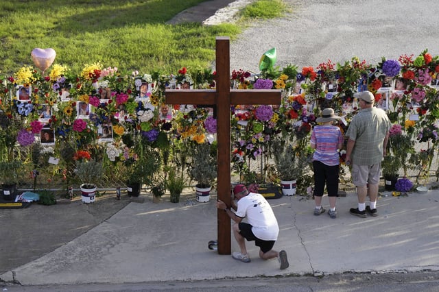 Dan Beazley, of Mich., prays with a large cross at a memorial for flood victims on Thursday, July 10, 2025, in Kerrville, Texas. (AP Photo/Ashley Landis)