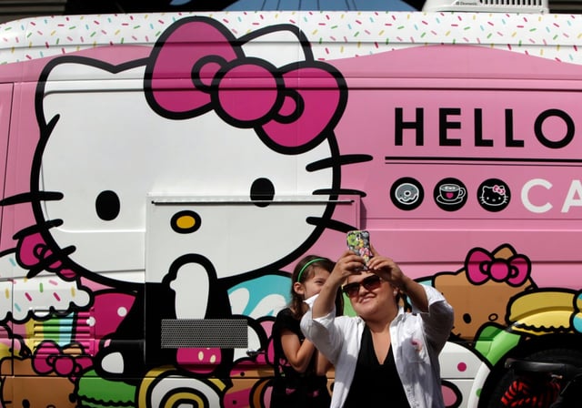 Sara Platero, of Scotts Valley, takes a selfie with her daughter Mia, 7, at the Hello Kitty Cafe Truck appearance in Santana Row on Sunday, April 19, 2015, in San Jose, Calif. Hundreds of people waited hours for a chance to buy sweets and goodies adorned with the trademark bows of the 40-year-old, mouthless kitten character. (Karl Mondon/Bay Area News Group)