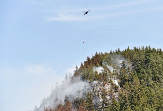 A helicopter battles wildfires in the hills north of Tantalus Road, in Squamish, British Columbia, Canada on June 11, 2025.