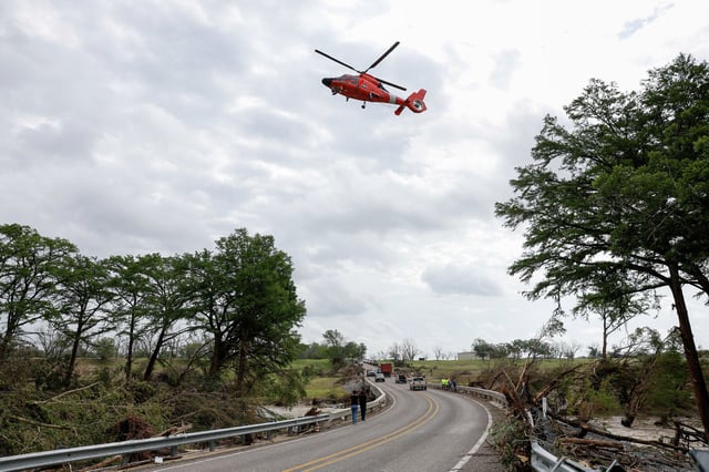 A U.S. Coast Guard helicopter flies over a bridge along the Guadalupe River in Center Point, Texas, Monday morning, July 7, 2025. The FAA ban, announced Thursday by the Texas Parks and Wildlife Department, comes after Kerrville city officials warned &#34;sightseers&#34; to keep away from the impacted areas.