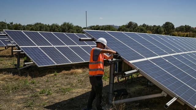 A worker checking solar panels near Chalcis, Greece on June 2. As part of a push for renewable energy, the country has installed 16 gigawatts of renewable energy, with solar power representing nearly 10 gigawatts, including 2.5 gigawatts that came on line last year.