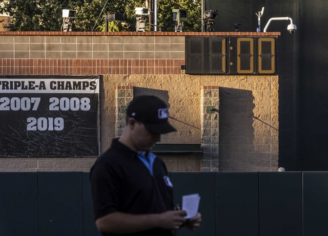 Third base umpire Steven Jaschinski checks his notes with an array of cameras, some used to track pitches, in the outfield during a game where an Automated Balls and Strikes System is used during play as the Sacramento River Cats played the Tacoma Rainiers at Sutter Health Park in Sacramento, Calif., on Tuesday May 28, 2024. 