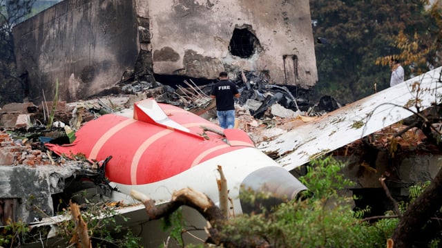 Ein Feuerwehrmann steht am Wrack einer abgestürzten Air-India-Maschine.