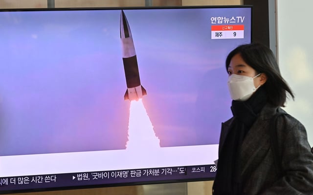 This image from January 20, 2022 shows a woman in Seoul, South Korea, walking past a news broadcast with file footage of a North Korean missile test.