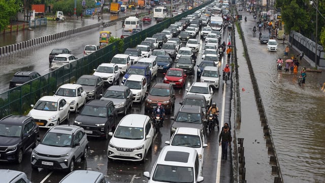 Traffic congestion on National Highway-48 due to waterlogging on the service road after heavy rain near the foot overbridge in Narsinghpur village, in Gurugram.