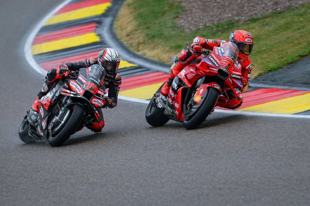 Le pilote espagnol Marc Marquez (à droite) double l'Italien Marco Bezzecchi (Aprilia) dans le dernier tour de la course sprint du Grand Prix d'Allemagne MotoGP sur le circuit du Sachsenring le 12 juillet 2025.