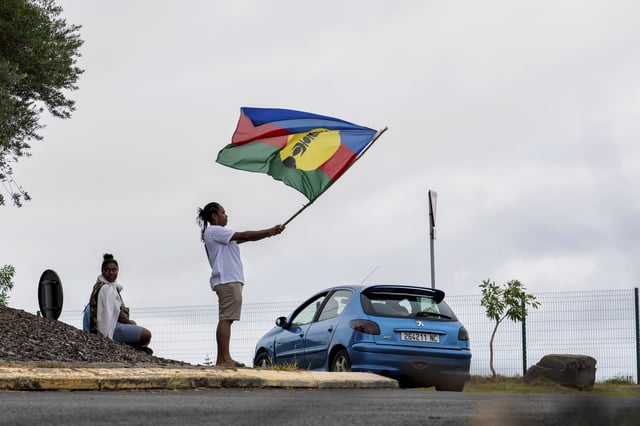 FILE - A woman waves a Kanak and Socialist National Liberation Front (FLNKS) flag in Noumea, New Caledonia, Wednesday May 15, 2024. (AP Photo/Nicolas Job, File)