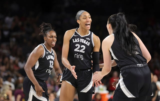 Las Vegas Aces center A’ja Wilson (22) celebrates with guard Chelsea Gray (12) and center Megan Gustafson, right, after making a basket and drawing a foul during the first half of a WNBA basketball game against the Golden State Valkyries, Saturday, July 12, 2025, in Las Vegas. (Steve Marcus/Las Vegas Sun via AP)
