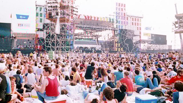 Tausende von Menschen sitzen während des Live-Aid-Konzerts am 13. Juli 1985 im JFK-Stadion in Philadelphia (USA) auf dem Boden.
