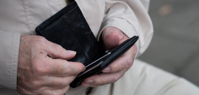 Ein Rentner hält sein Portemonnaie in der Hand