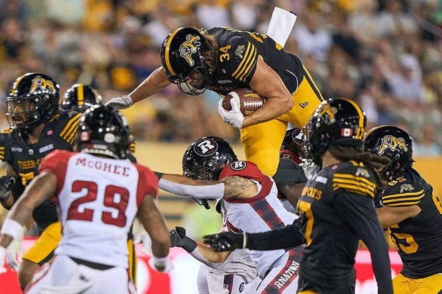 Hamilton Tiger-Cats' Ante Milanovic-Litre jumps over Ottawa Redblacks defenders during second half CFL action in Hamilton, Ont. on Saturday, July 12, 2025.