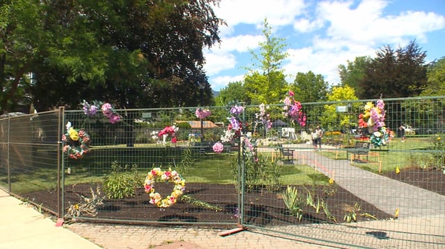 Flower wreaths line a temporary fence around the Rise Memorial Garden.