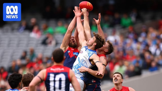 A large pack of Melbourne and North Melbourne players collide while reaching towards the ball in the air