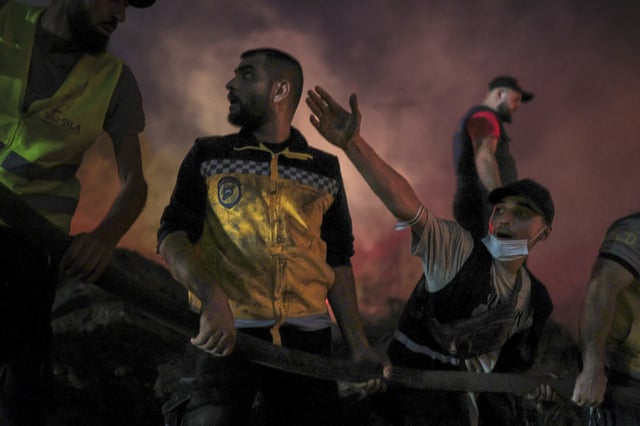 Syrian Civil Defense teams and volunteers battle wildfire flames for the tenth consecutive day near the town of Kasab, in Syria's Latakia countryside, early Saturday, July 12, 2025. (AP Photo/Ghaith Alsayed)
