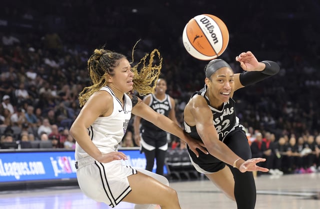 Las Vegas Aces center A'ja Wilson (22) loses control of the ball after being fouled by Golden State Valkyries guard Veronica Burton, left, during the first half of a WNBA basketball game Saturday, July 12, 2025, in Las Vegas. (Steve Marcus/Las Vegas Sun via AP)
