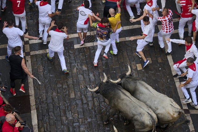Revelers run alongside José Escolar Gil's fighting bulls during the sixth running of the bulls at the San Fermín Festival in Pamplona, Spain, Saturday, July 12, 2025. (AP Photo/Miguel Oses)