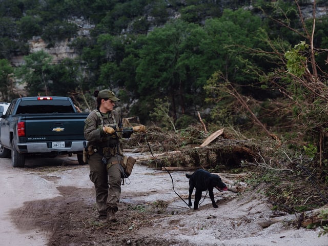 A K9 unit with the Texas Game Warden conducts searches in flood damaged areas next to Camp Mystic in Hunt on July 5. Searches on Sunday were halted because of a new flooding threat.